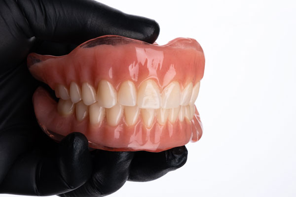 Pair of upper and lower false teeth set also known as complete denture held in hand